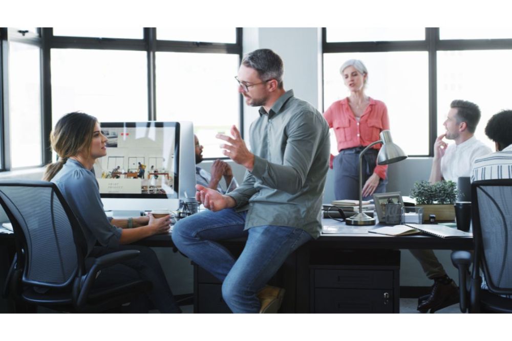homme assis au bureau parlant avec sa collegue